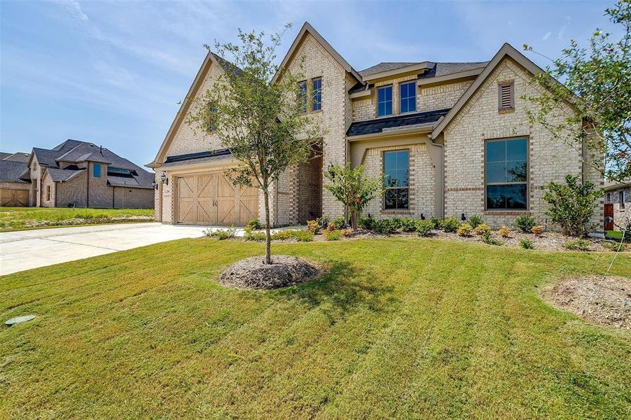 View of front of property featuring a front lawn and a garage