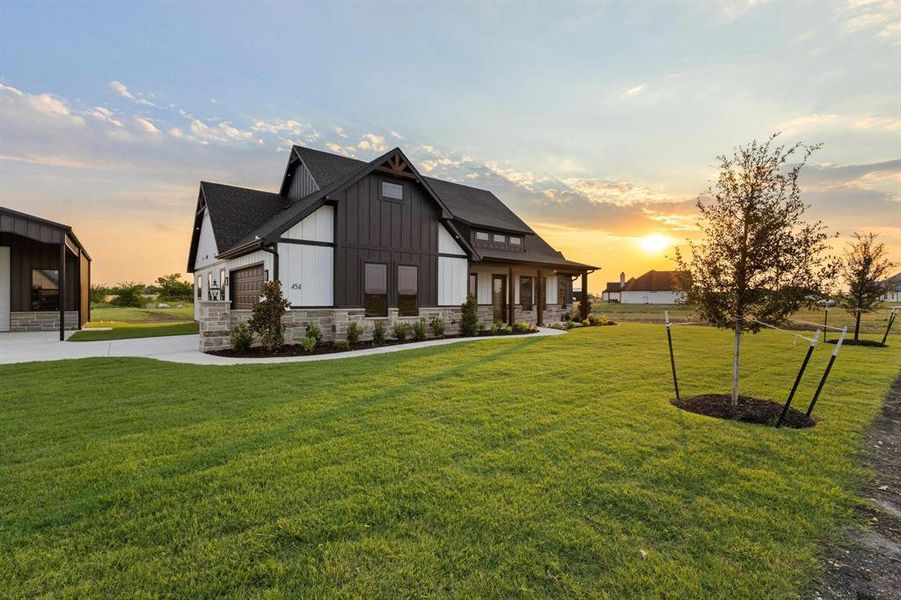 Back of property featuring board and batten siding, a yard, stone siding, and covered porch