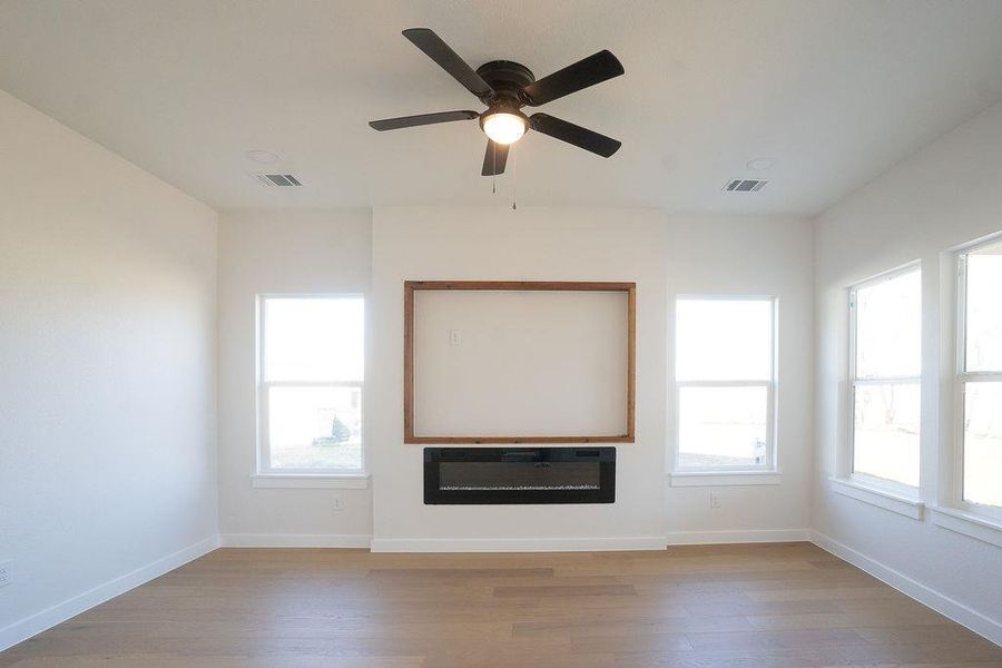 Unfurnished living room featuring wood finished floors, healthy amount of natural light, and ceiling fan