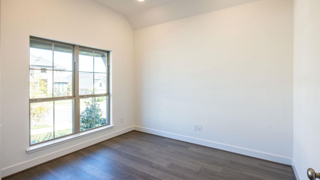 Empty room with dark wood-style flooring and lofted ceiling Empty room with dark wood-style flooring and lofted ceiling