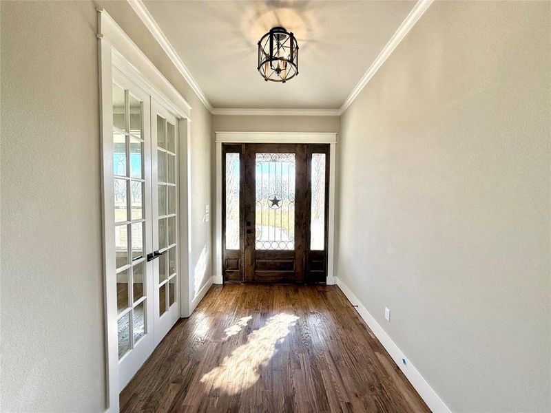 Foyer entrance featuring dark wood finished floors, ornamental molding, and french doors Foyer entrance featuring dark wood finished floors, ornamental molding, and french doors