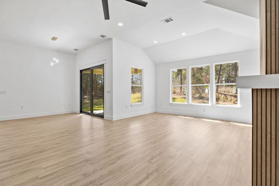 Unfurnished living room featuring light wood-type flooring, a ceiling fan, plenty of natural light, recessed lighting, and vaulted ceiling