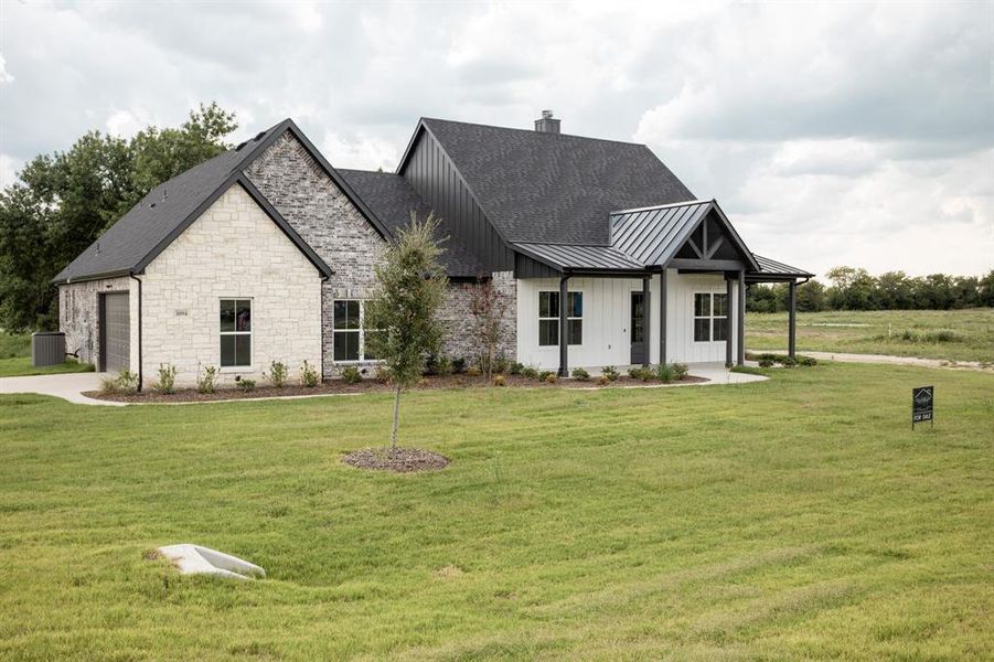 Modern farmhouse with a standing seam roof, covered porch, a front lawn, and concrete driveway Modern farmhouse with a standing seam roof, covered porch, a front lawn, and concrete driveway