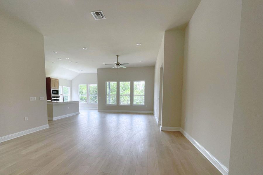 An open floorplan living area flows seamlessly into the kitchen, illuminated by ample windows.