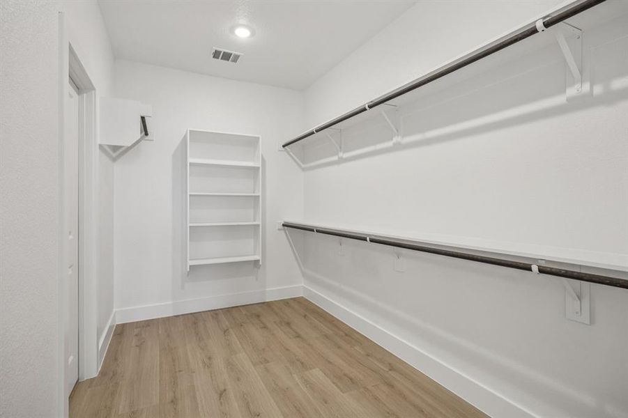Spacious closet with light wood-type flooring Spacious closet with light wood-type flooring