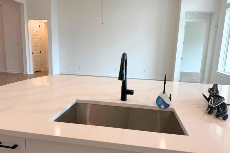 Kitchen view of a sink and light stone counters