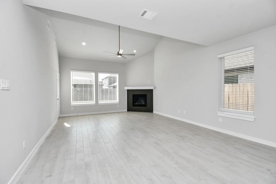 Welcome family and guests to your charming living room! With its high ceilings, recessed lighting, ceiling fan, custom paint, beautiful flooring, and large windows that let in abundant natural light, this room is perfect for gatherings. Sample photo of completed home with similar floor plan. Actual colors and selections may vary.