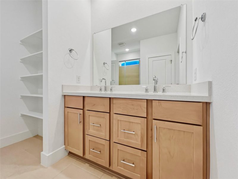 Bathroom featuring double vanity, light tile patterned flooring, a closet, and a stall shower