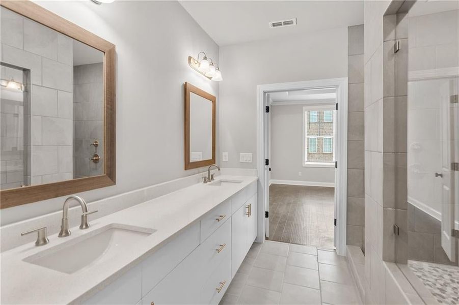 The luxurious owners bath at homesite 102 features a double vanity in Riverstone gray and marble countertops with undermount sinks. It will also have a walk in tile shower and a separate soaking tub.  Photos are not of the exact property but are similar,