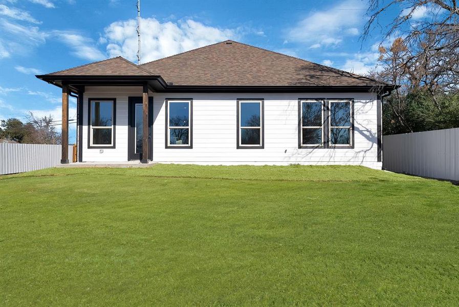 Back of house featuring a fenced backyard, a patio, and a shingled roof
