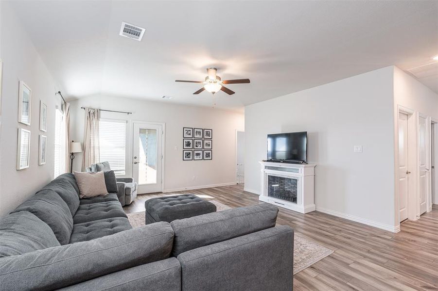 Living room featuring light wood-style flooring, visible vents, baseboards, and a glass covered fireplace