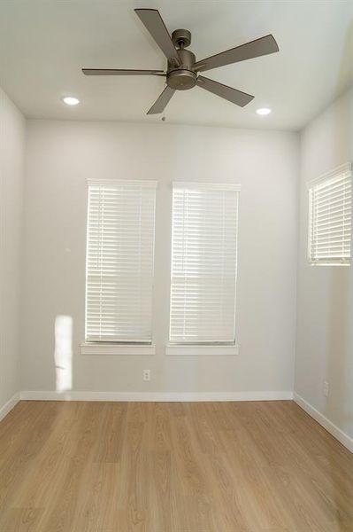 Room featuring five-blade ceiling fan, recessed lighting, and wood-finish flooring Room featuring five-blade ceiling fan, recessed lighting, and wood-finish flooring