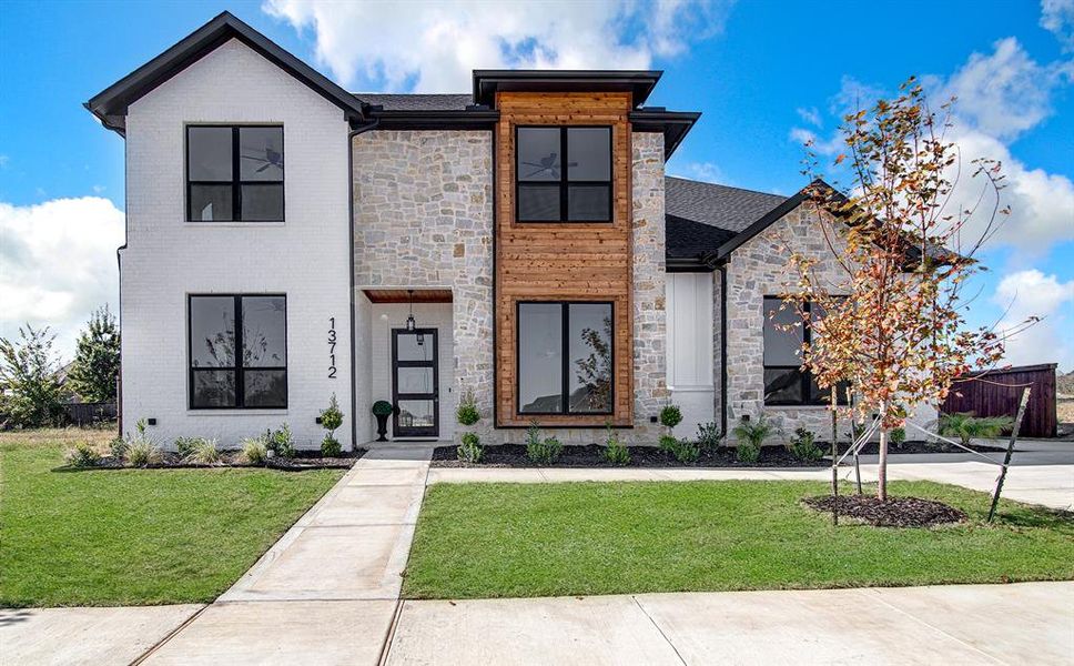 Contemporary house featuring stone siding, a front lawn, and roof with shingles Contemporary house featuring stone siding, a front lawn, and roof with shingles