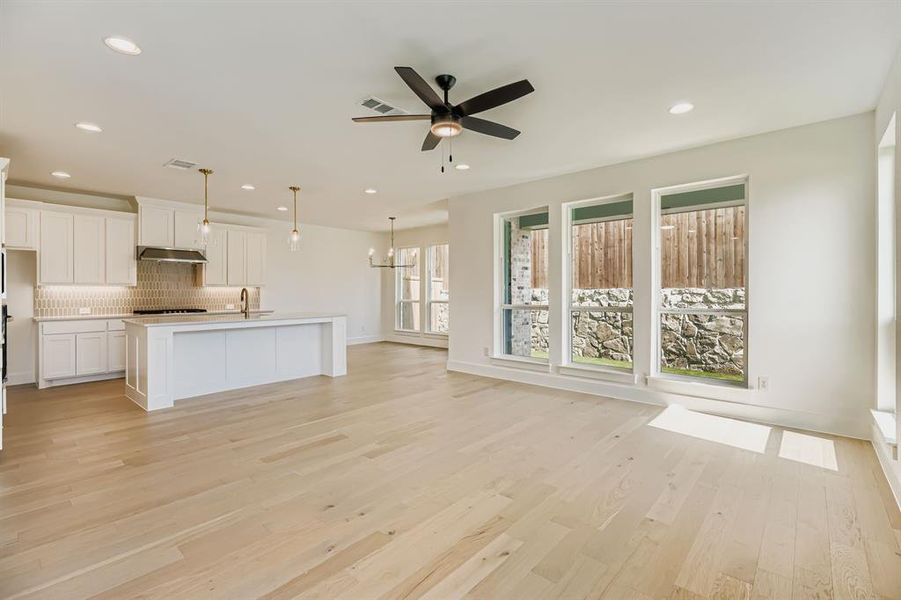Unfurnished living room featuring recessed lighting, a ceiling fan, light wood-style floors, and a chandelier