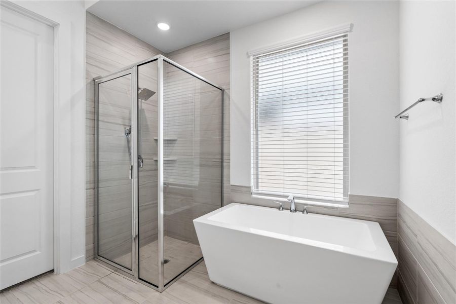 Modern bathroom featuring a frameless glass shower and a sleek freestanding bathtub. The space is bright with neutral tiles and a window with blinds, creating a clean and inviting atmosphere. Modern bathroom featuring a frameless glass shower and a sleek freestanding bathtub. The space is bright with neutral tiles and a window with blinds, creating a clean and inviting atmosphere.