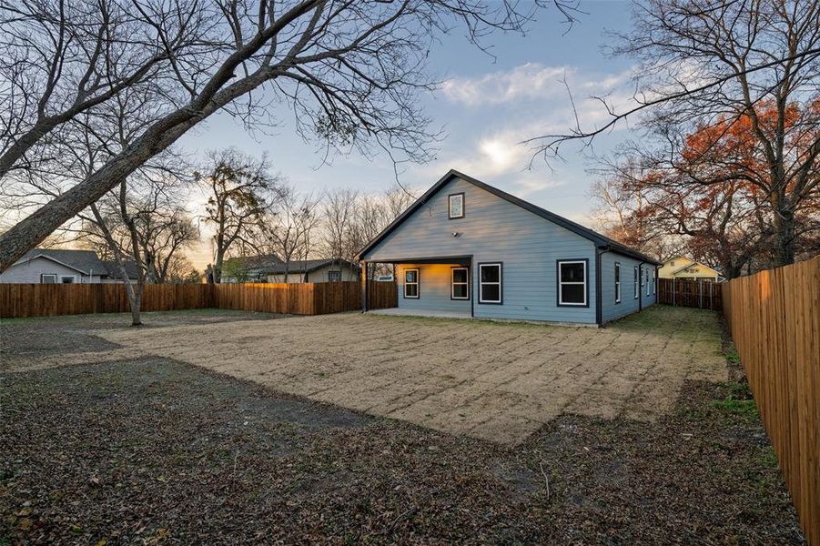 Back of property at dusk featuring a patio and a fenced backyard