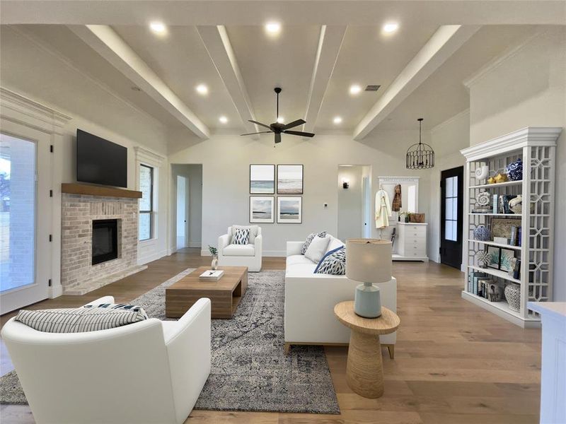 Living room featuring ceiling fan with notable chandelier, a fireplace & a wealth of natural light,