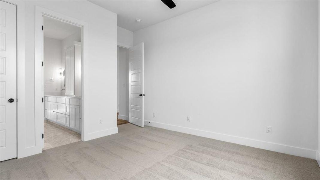 Unfurnished bedroom featuring ceiling fan, light colored carpet, and connected bathroom