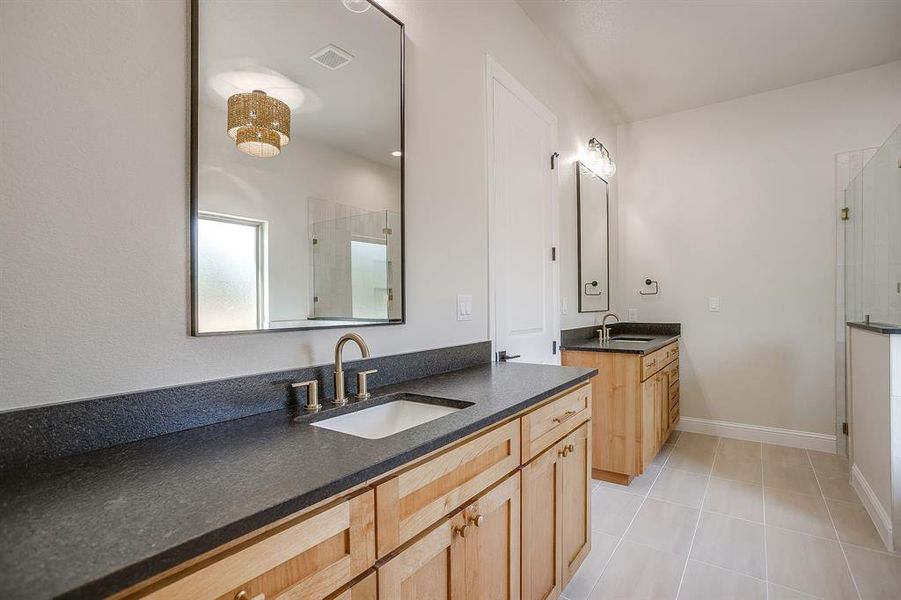 Bathroom featuring a stall shower, two vanities, and light tile patterned floors Bathroom featuring a stall shower, two vanities, and light tile patterned floors