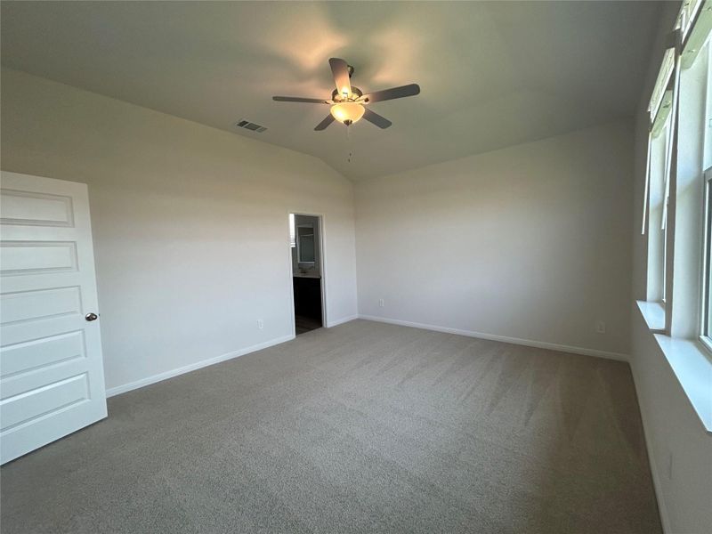 Carpeted empty room featuring vaulted ceiling and a ceiling fan Carpeted empty room featuring vaulted ceiling and a ceiling fan
