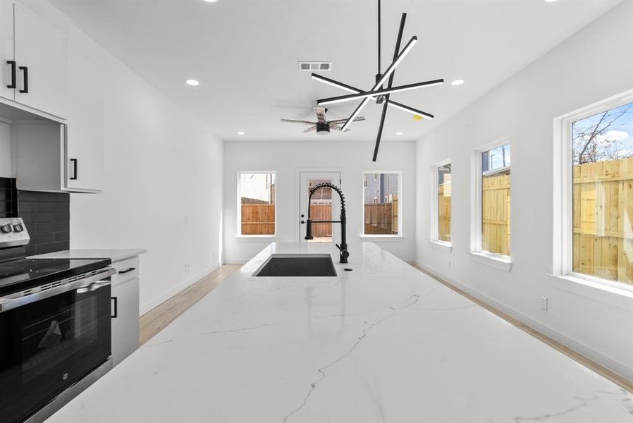 Kitchen with visible vents, light stone counters, stainless steel electric range, a sink, and recessed lighting