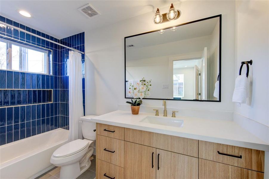 1st Floor Full Bathroom attached to 1st Floor Bedroom. Designer tilework, soft-close European style cabinetry with quartz counters. Delta champagne bronze shower fixtures.