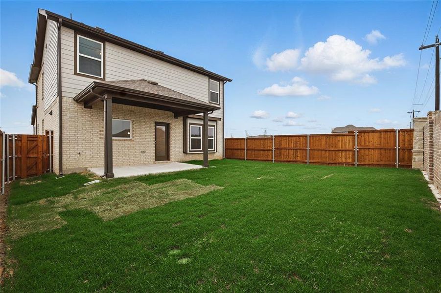 Back of house featuring a fenced backyard, a patio, and brick siding