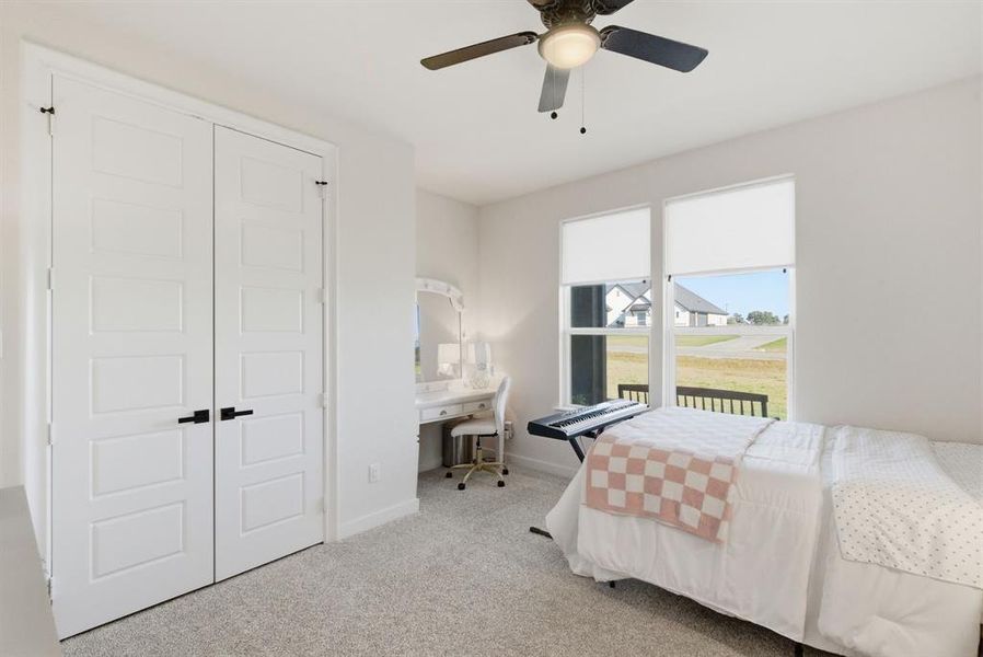 Bedroom featuring light carpet, an office area, a ceiling fan, and a closet