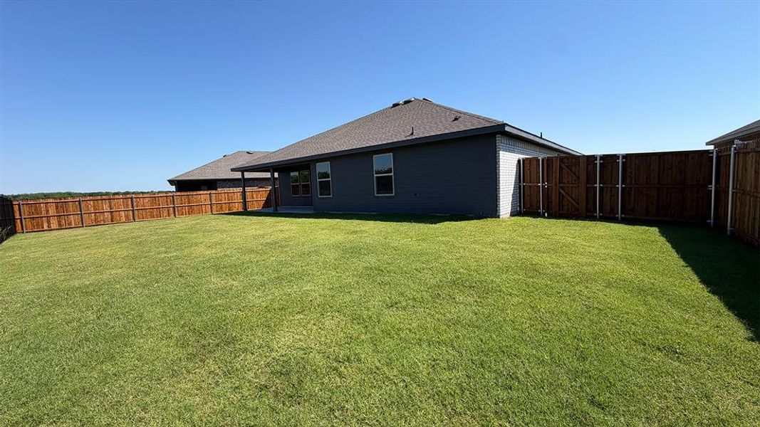 Expansive grassy backyard featuring a full privacy fence Expansive grassy backyard featuring a full privacy fence