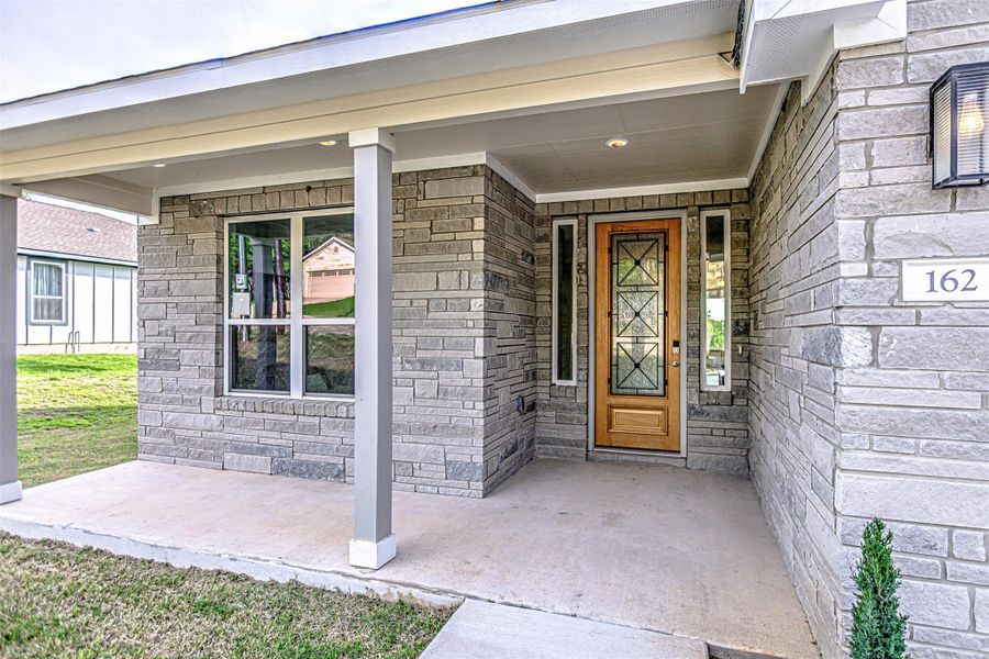 View of exterior entry featuring stone siding and a covered porch