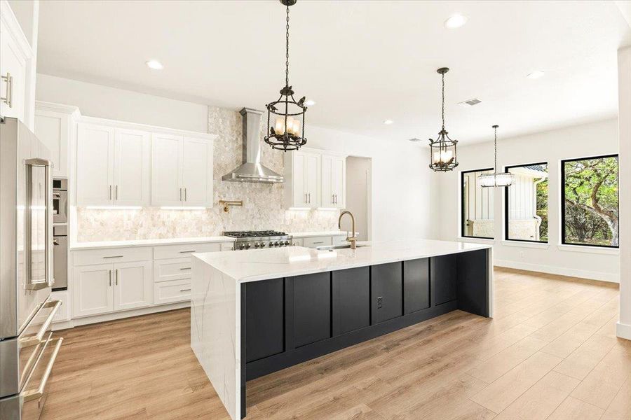 A well-appointed kitchen features a grand island, abundant cabinetry, and luminous flooring.