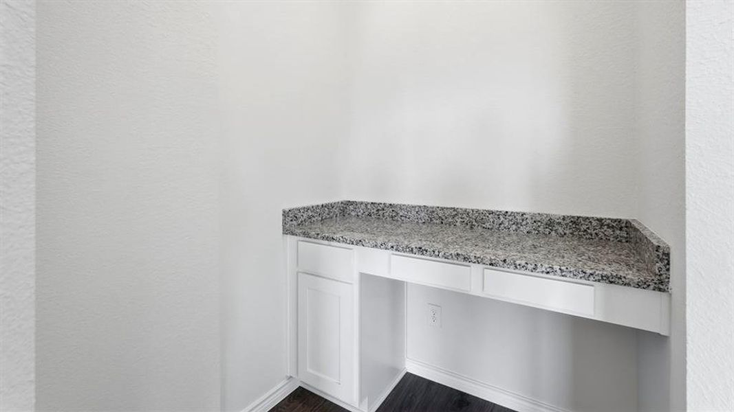 Detailed view of a textured wall, built in desk, and wood finished floors Detailed view of a textured wall, built in desk, and wood finished floors
