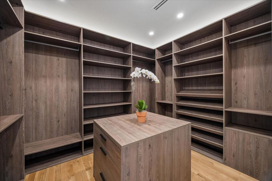 Second walk-in closet with custom wood shelving, ample storage, and a central island for organization. Second walk-in closet with custom wood shelving, ample storage, and a central island for organization.