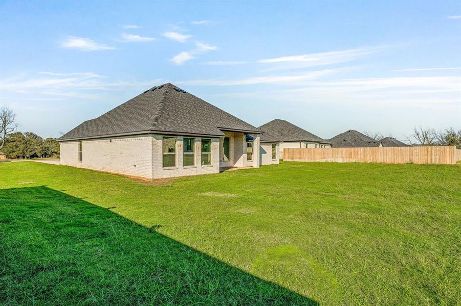 Rear view of property featuring roof with shingles, a patio, and brick siding