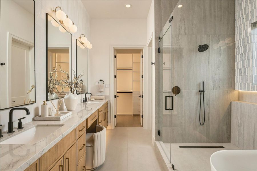The primary bath delivers a spa-like experience with a generous dual vanity, dedicated makeup station, and an oversized frameless glass shower with a ceiling-mounted rainfall showerhead.
