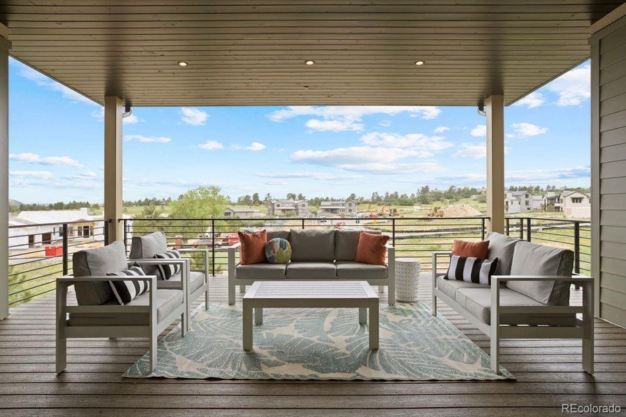 Covered outdoor living space with a modern railing, and expansive views of the surrounding landscape.
