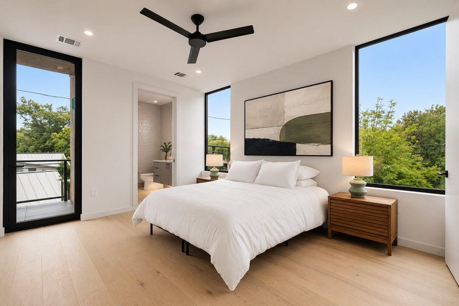 Natural light floods this modern primary bedroom, featuring a private balcony and a seamless transition to an en-suite bathroom.