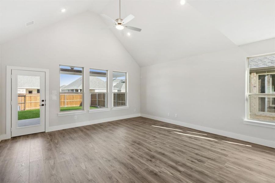 Unfurnished living room with high vaulted ceiling, light wood-type flooring, a wealth of natural light, and ceiling fan