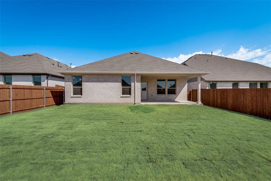 Rear view of property with a lawn and a patio