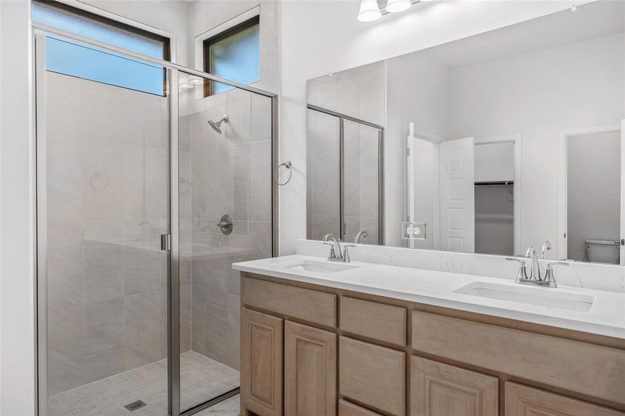 Bathroom with double vanity, a stall shower, and a spacious closet Bathroom with double vanity, a stall shower, and a spacious closet