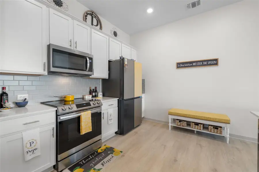 Kitchen featuring stainless steel appliances, white cabinetry, light wood-type flooring, decorative backsplash, and recessed lighting Kitchen featuring stainless steel appliances, white cabinetry, light wood-type flooring, decorative backsplash, and recessed lighting