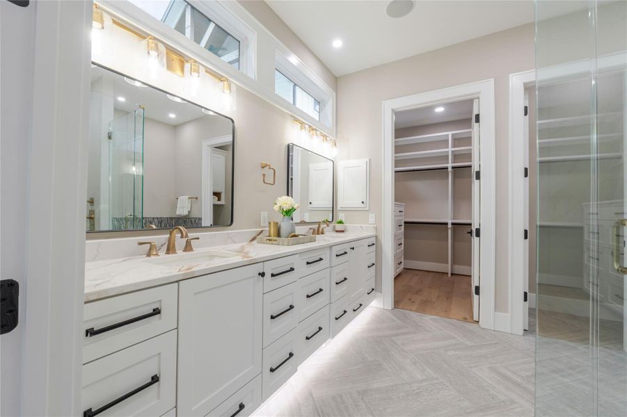 Full bath with double vanity, parquet flooring, a spacious closet, recessed lighting, and a stall shower