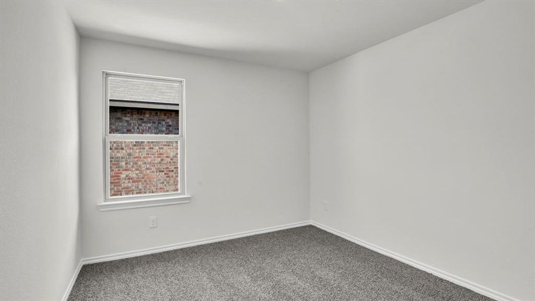 Neutral-toned room featuring a single window with white trim, light gray textured carpeting, and bright white walls