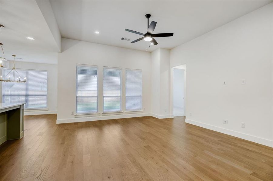 Spacious living area featuring wood-finish flooring, vaulted ceilings, and a modern ceiling fan