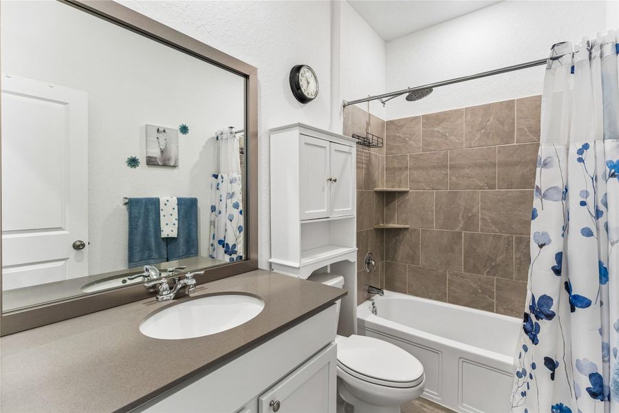 Bathroom featuring a white vanity with a rectangular undermount sink, a gray countertop, and a large framed mirror Bathroom featuring a white vanity with a rectangular undermount sink, a gray countertop, and a large framed mirror