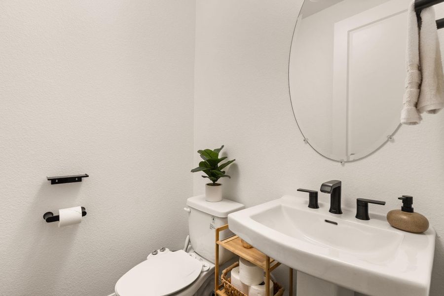 White pedestal sink with matte black faucet and fixtures