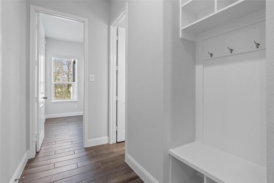 Step into this highly functional and stylish mudroom drop zone, an essential feature for a busy household. The space boasts custom-built white cabinetry and shelving, providing generous storage for coats, bags, and shoes. A comfortable built-in bench offers a convenient spot to sit, while three sleek hooks keep outerwear tidy and accessible. Step into this highly functional and stylish mudroom drop zone, an essential feature for a busy household. The space boasts custom-built white cabinetry and shelving, providing generous storage for coats, bags, and shoes. A comfortable built-in bench offers a convenient spot to sit, while three sleek hooks keep outerwear tidy and accessible.