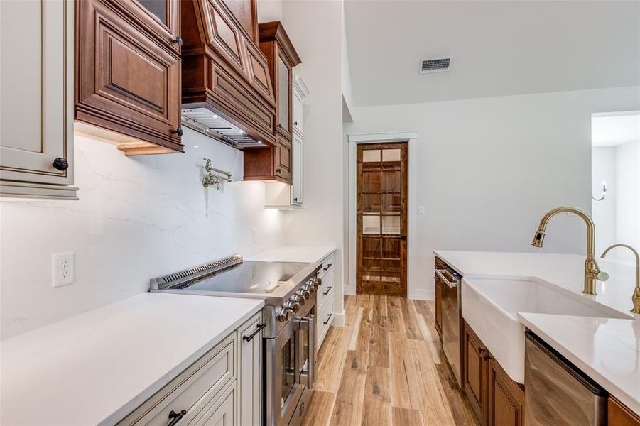 Kitchen with premium range hood, quartz countertops, appliances with stainless steel finishes, and sink