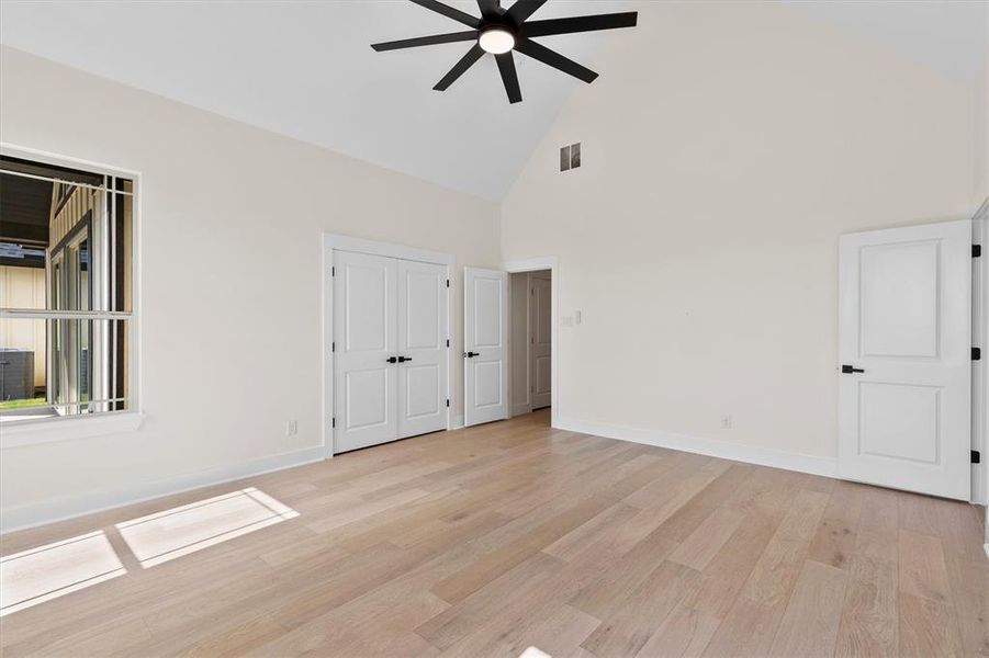 Unfurnished room with high vaulted ceiling, a ceiling fan, light wood-style flooring, and baseboards Unfurnished room with high vaulted ceiling, a ceiling fan, light wood-style flooring, and baseboards