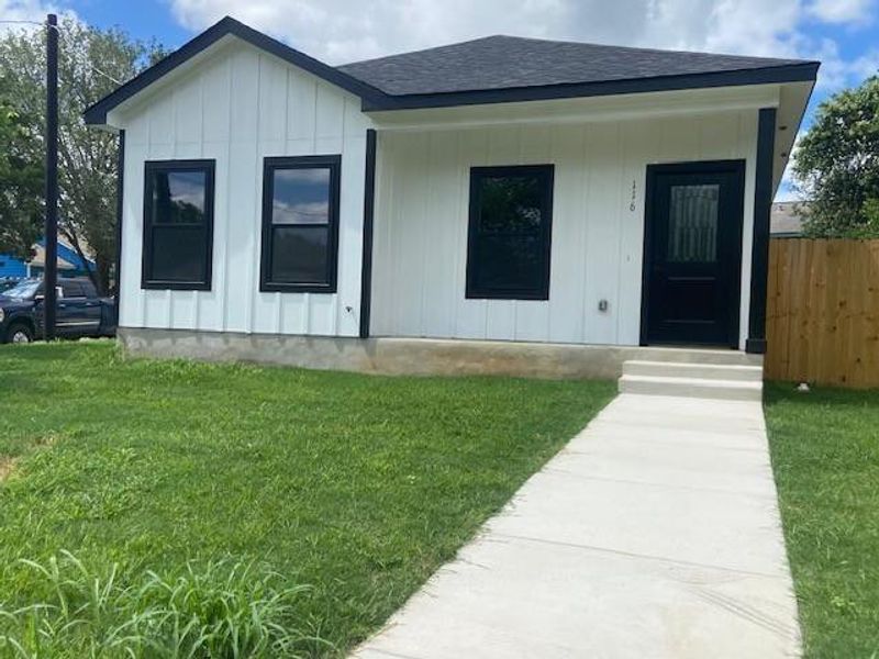 A quaint residence featuring white board and batten siding, black trim, and a welcoming sidewalk. A quaint residence featuring white board and batten siding, black trim, and a welcoming sidewalk.